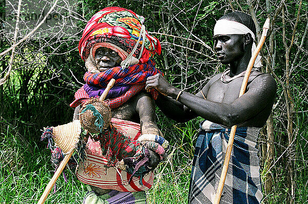 Ein Mursi-Stammesangehöriger hält seine Donga (hölzerne Duellstange)  während er seine Tumoga (Duellausrüstung) während eines Thagine-Wettbewerbs (zeremonielles Duell) befestigt; Makki  Äthiopien
