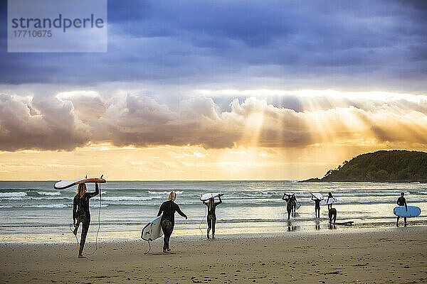 Ein wunderschöner Sonnenaufgang begrüßt die Surfer  die sich auf das morgendliche Surfen vorbereiten und hinauspaddeln; Arrawarra  New South Wales  Australien