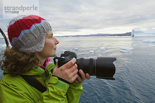 Frau auf mitternächtlicher Kreuzfahrt durch den Ilulissat-Eisfjord  eine Unesco-Welterbestätte. Grönland.