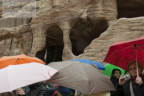 Eine Gruppe von Touristen sucht während eines Regensturms Schutz unter Regenschirmen in der Unesco-Weltkulturerbestätte Petra  einem der neuen sieben Weltwunder; Petra  Jordanien