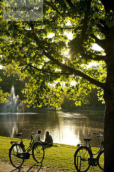Paar entspannt sich neben dem See im Vondelpark am Abend; Amsterdam  Holland
