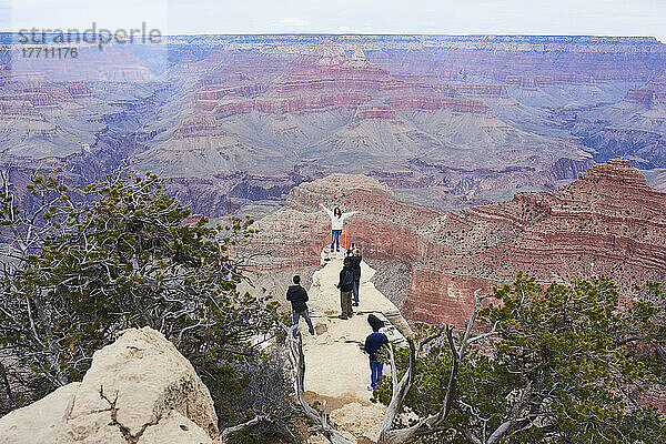 Weiblicher Tourist mit erhobenen Händen posiert für ein Foto auf einem Felsvorsprung im Grand Canyon; Arizona  Vereinigte Staaten von Amerika