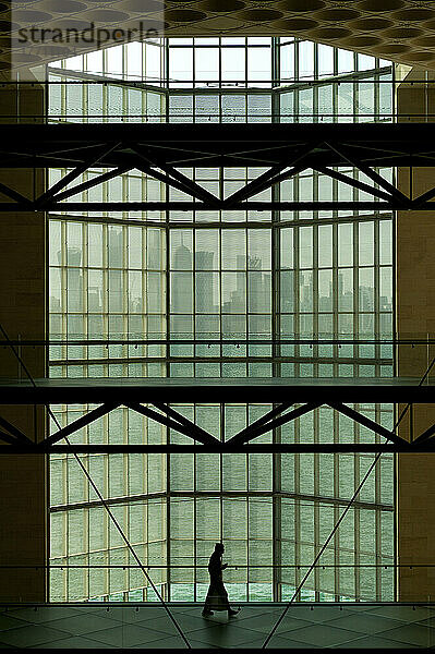 Silhouette eines Mannes vor einem großen Fenster im Museum für islamische Kunst mit Blick auf die moderne Stadtsilhouette von Doha; Doha  Katar