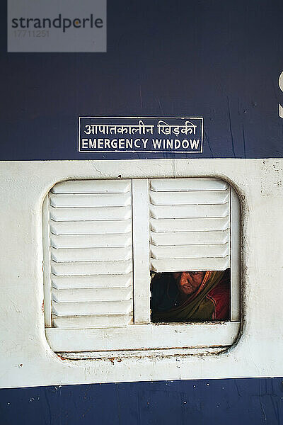 Eine Frau schaut aus dem Notfenster eines Zuges; Indien