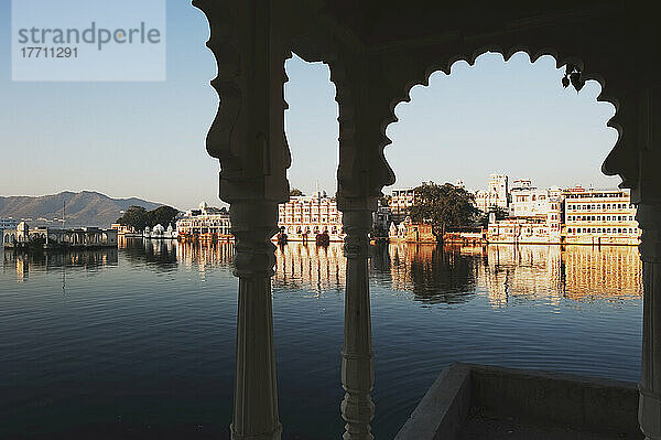 Ansicht von Gebäuden entlang der Uferlinie eines Flusses  eingerahmt von einem Torbogen; Udaipur  Indien