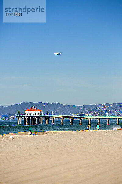 Ein sonniger Nachmittag am Manhattan Beach Pier  Kalifornien. Ein Flugzeug hebt vom LAX im Hintergrund ab; Manhattan Beach  Kalifornien  Vereinigte Staaten von Amerika