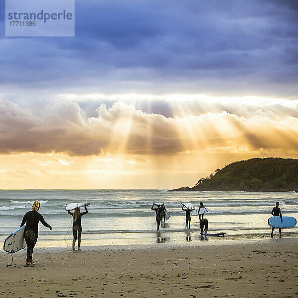 Ein wunderschöner Sonnenaufgang begrüßt die Surfer  die sich auf das morgendliche Surfen vorbereiten und hinauspaddeln; Arrawarra  New South Wales  Australien