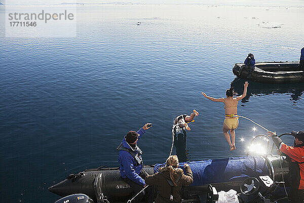 Touristen springen von einem Boot in das eiskalte Wasser des Arktischen Ozeans; Svalbard  Norwegen