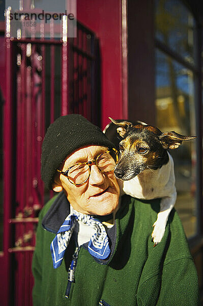 Ein älterer Mann geht mit seinem Hund auf den Schultern spazieren  Portobello Road Market; London  England