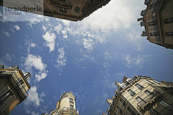 Low Angle View Of The Tops Of Various Buildings Against A Blue Sky With Cloud; Paris  Frankreich