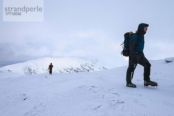 Frau und Mann wandern auf dem Beinn Dorain bei verschneiten  winterlichen Bedingungen in der Nähe der Bridge of Orchy; Argyll und Bute  Schottland