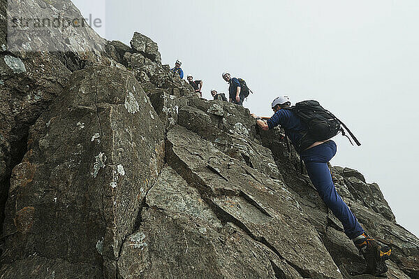 Wanderer kraxeln den steilen Felsen in der Nähe des Gipfels von Sgurr Alasdair in den Black Cuillin hinauf; Isle Of Skye  Schottland