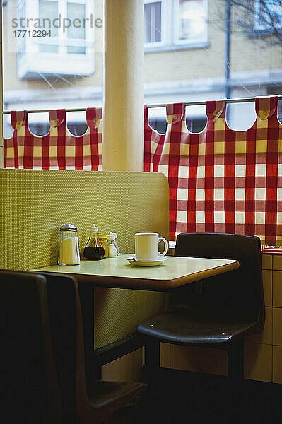 Ein Restaurant mit rot-weiß-karierten Vorhängen am Fenster und einer gelben Wand; London  England