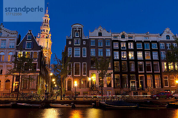 Giebelhäuser in der Abenddämmerung mit der Kirchturmspitze der Zuiderkerk dahinter; Amsterdam  Holland