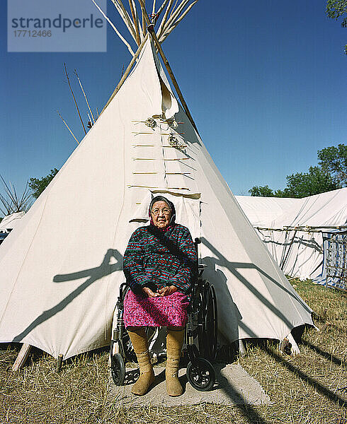 Ältere Crow-Frau in traditionellem Gewand vor dem Tipi ihrer Familie während der jährlichen Crow-Messe (August)  dem größten indianischen Fest in den USA. Die Crow (Apsaaloke  Apsaroke oder Absaroke) leben im Crow-Reservat (Montana  USA).