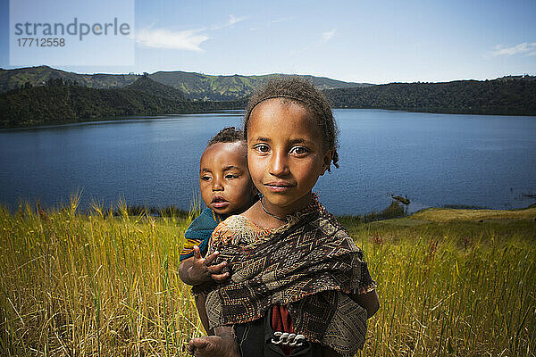 Junges Mädchen mit Baby auf dem Rücken in einem Weizenfeld  Wenchi-Krater und See  westlich von Addis Abeba; Äthiopien