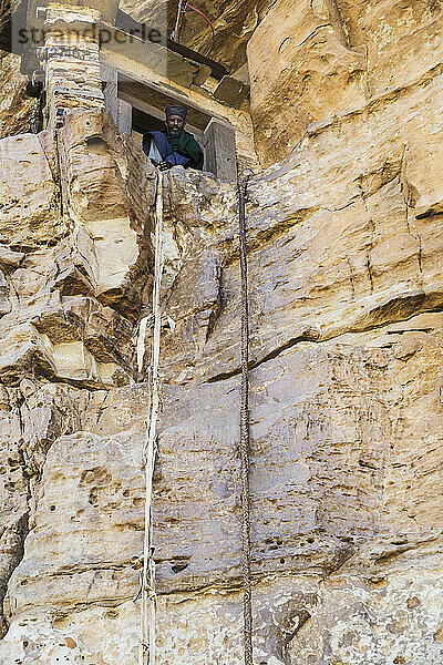 Ein Mann schaut aus dem Fenster von einer in den Fels gehauenen Klippe; Lalibela  Äthiopien