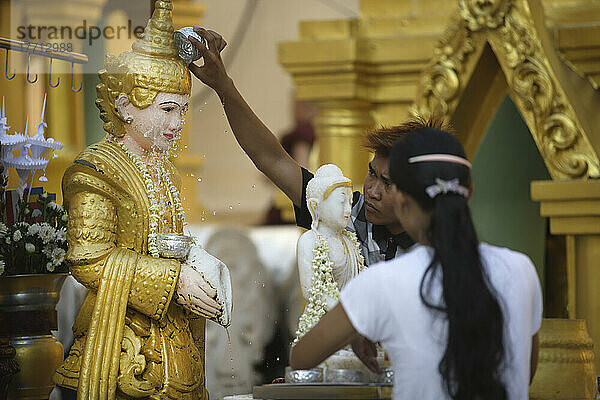 Menschen baden oder bespritzen eine Buddha-Statue in der Shwedagon-Pagode; Yangon  Birma