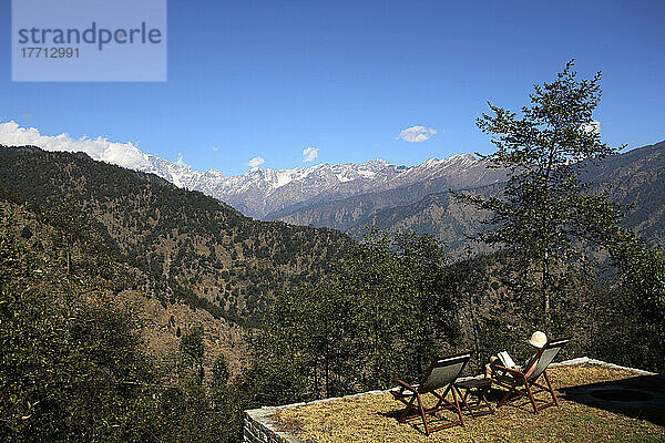 Ein Tourist sitzt da und liest ein Buch mit Blick auf den indischen Himalaya; Uttaranchal  Indien