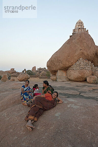 Drei Frauen und ein Mädchen sitzen auf einem Felsen und blicken auf die Landschaft; Hampi  Karnataka  Indien