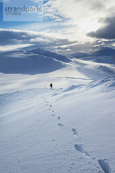 Wanderer auf einem verschneiten Winterspaziergang beim Abstieg vom Creag Pitridh  in der Nähe von Laggan; Schottland