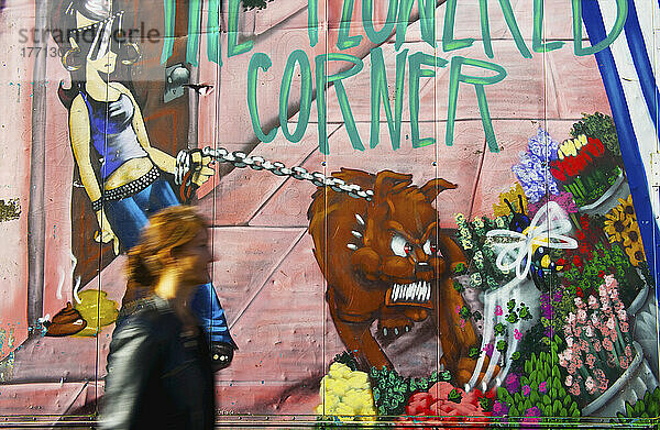 Eine Frau geht an einer mit einem bunten Wandgemälde bemalten Wand vorbei  Portobello Road Market; London  England