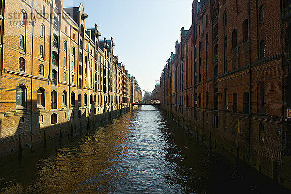 Braune Backsteingebäude entlang eines Kanals unter blauem Himmel; Hamburg  Deutschland