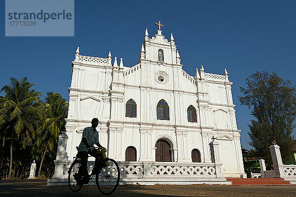 Silhouette eines Mannes auf einem Fahrrad vor einer alten portugiesischen Kirche; Goa  Indien