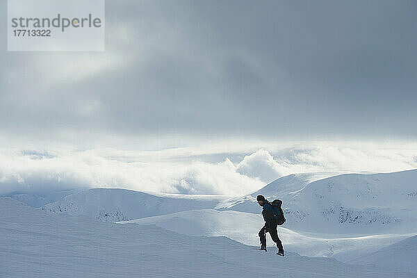 Wanderer auf verschneitem Winterspaziergang beim Aufstieg zum Geal Charn  in der Nähe von Laggan; Schottland
