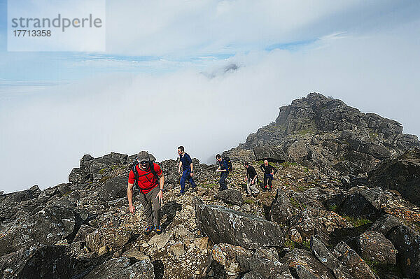 Wanderer  die in der Nähe des Gipfels von Sgurr Nan Eag  einem der Gipfel der Black Cuillin  über den Wolken auftauchen; Isle of Skye  Schottland
