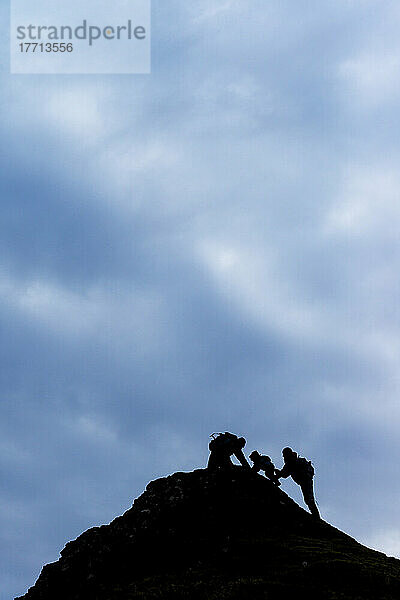 Silhouette eines Paares  das einem kleinen Jungen beim Klettern hilft; Kerrera Island  Schottland