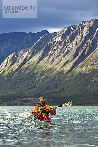 Kajakfahrer auf dem Kusawa-See mit der untergehenden Sonne  die auf die Berge trifft; Yukon  Kanada