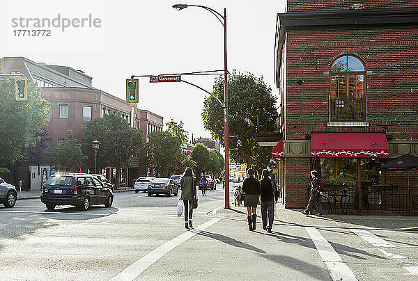 Ein junges Paar beim Überqueren der Straße in der Innenstadt; Victoria  Vancouver Island  British Columbia