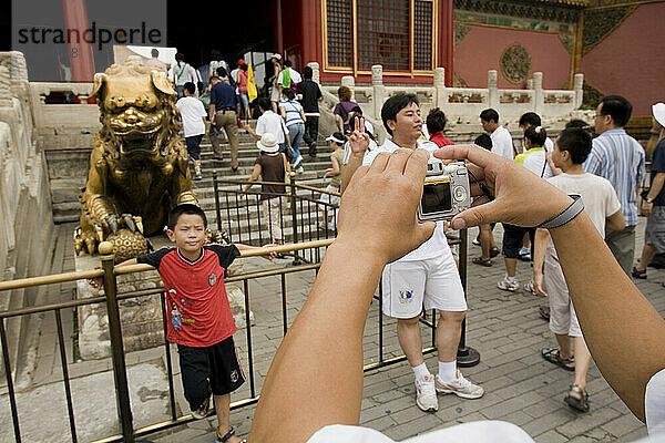 Touristen fotografieren einen der vergoldeten Löwen vor dem Palast der ruhigen Langlebigkeit  Peking  China