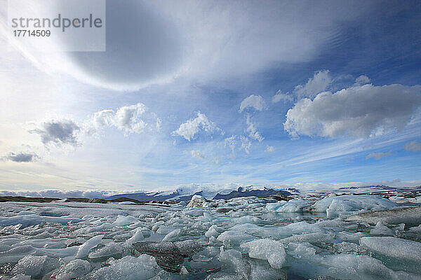 Die schmelzenden Eisberge von Jokulsarlon  der Gletscherlagune in Südisland mit linsenförmigen Wolken über ihnen