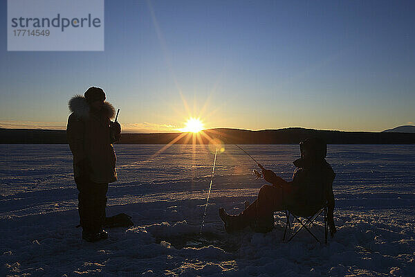 Silhouetten von Menschen Eisfischen auf Teslin Lake bei Sonnenuntergang  Yukon