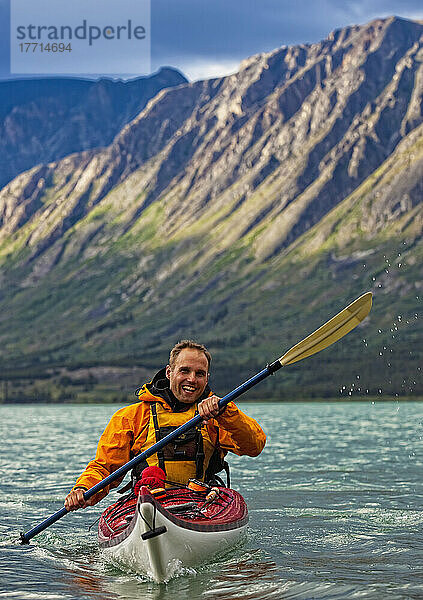 Kajakfahrer auf dem Kusawa-See mit der untergehenden Sonne  die auf die Berge trifft; Yukon  Kanada