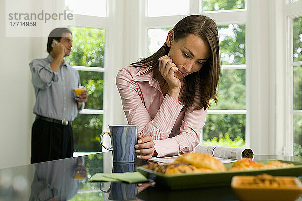Frau lesend  Mann am Handy in der Küche