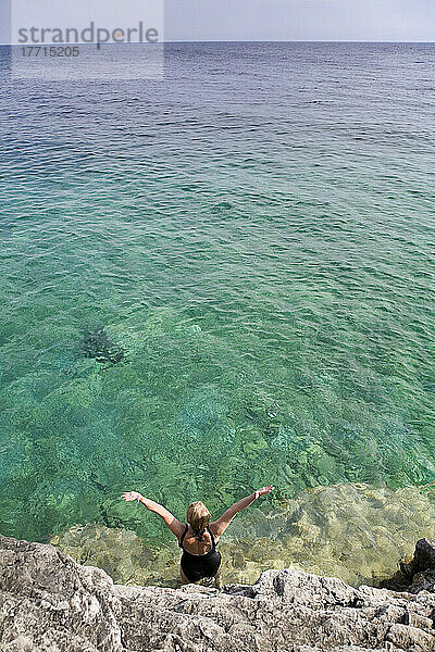 Frau hebt ihre Arme in den Himmel an der felsigen Küste im Bruce Peninsula National Park; Ontario  Kanada