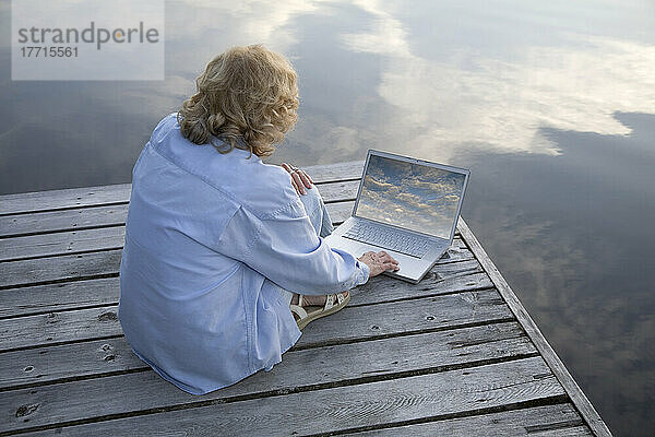 Frau benutzt Laptop am Cottage Dock  Ontario