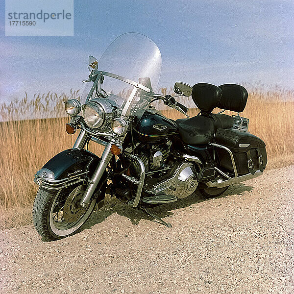 Am Rande einer Schotterstraße geparktes Motorrad auf einem Acker in der Landschaft; Manitoba  Kanada