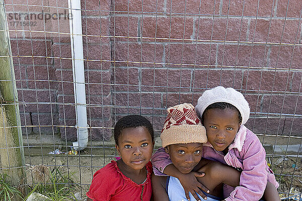 Kinder sitzen an einem Zaun  Kapstadt  Südafrika