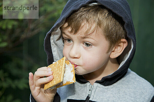 Junger Junge  der versucht  ein klebriges S'more im Freien zu essen; Edmonton  Alberta  Kanada