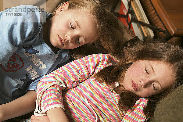 Zwei junge Mädchen schlafen auf der Couch