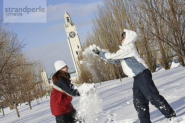Mädchen spielen im Schnee mit Uhrenturm im Hintergrund