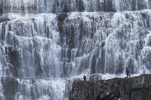 Ein Ehepaar geht vor dem Wasserfall Dynjandi spazieren; Westfjorde  Island