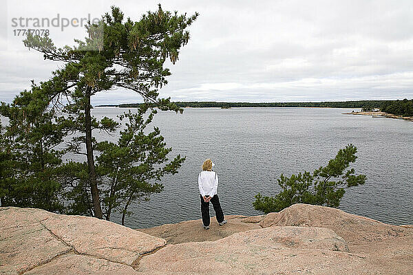 Frau  die auf einem Felsvorsprung mit Blick auf die Georgian Bay im Killbear Provincial Park steht; Ontario  Kanada