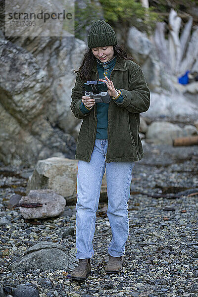 Junge Frau steht mit der Fernsteuerung für eine Drohne im Whytecliff Park  Horseshoe Bay; British Columbia  Kanada