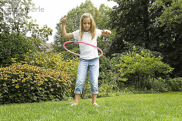 Junges Mädchen spielt mit ihrem Hula-Hoop-Reifen im Garten; Ontario Kanada