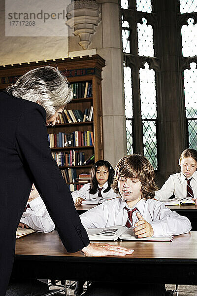 Lehrer im Gespräch mit Schüler im Klassenzimmer